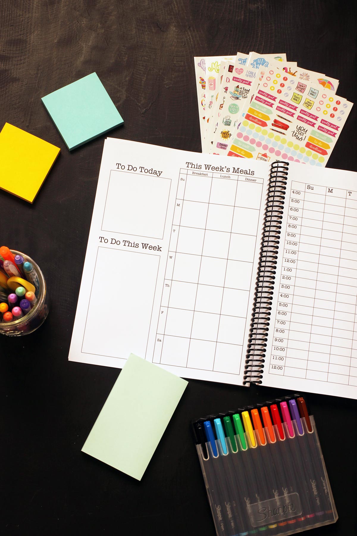 open Print & Go Planner with weekly meal plan blanks on table with stickers, post-it notes, and markers.