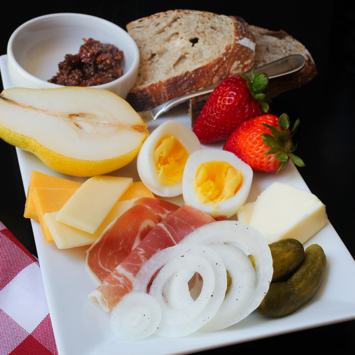 ploughman's lunch on a rectangular platter with fruit and veg and egg.