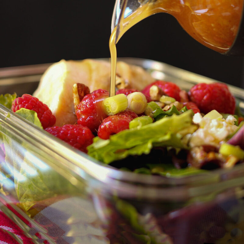 drizzling raspberry vinaigrette on raspberry salad.