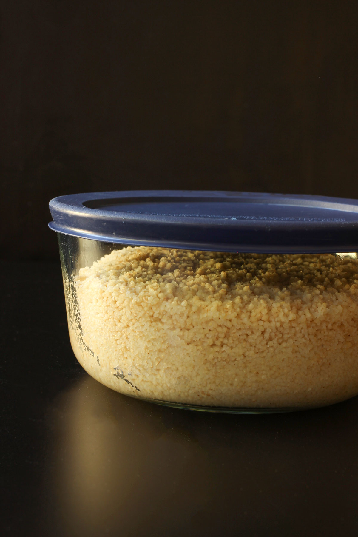 couscous absorbing broth in glass bowl with lid.