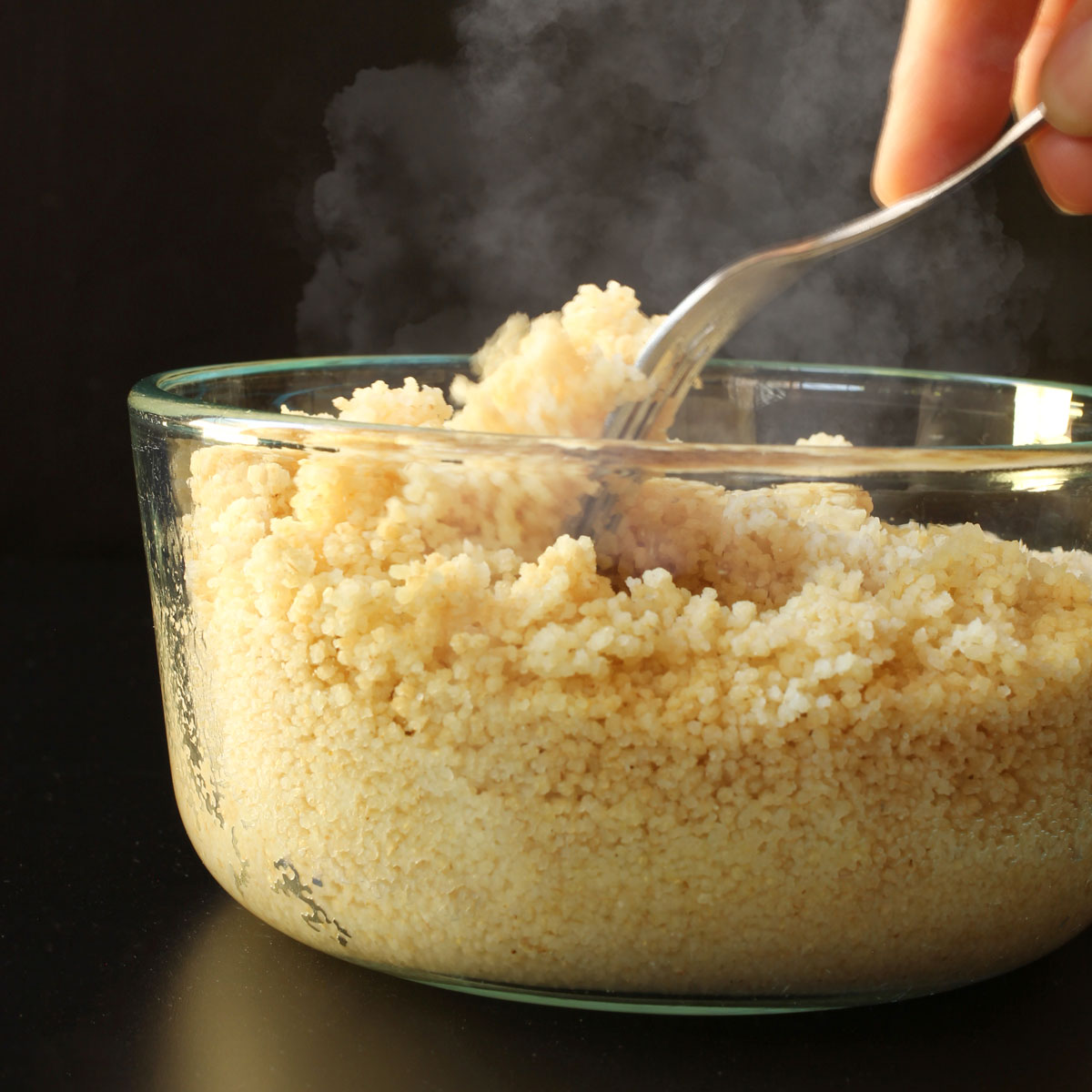 fluffing cooked couscous with a fork.