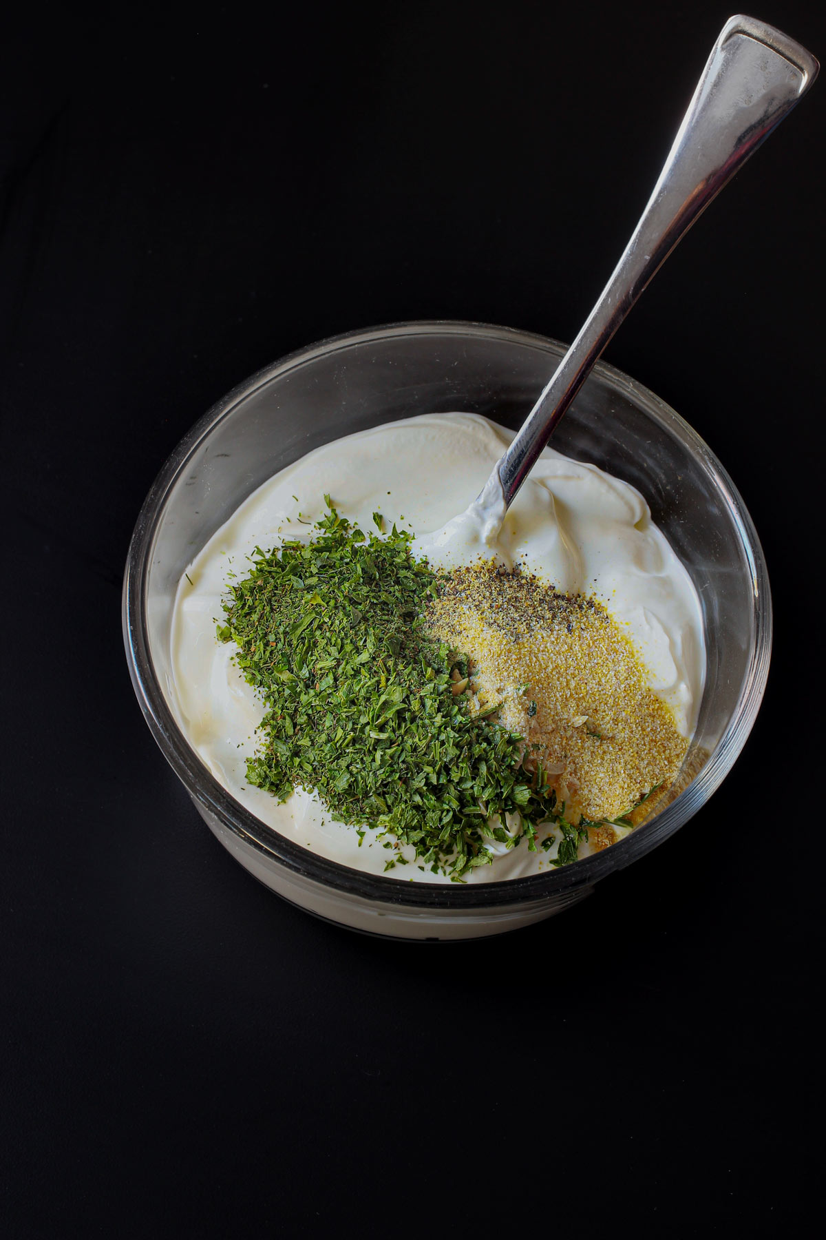 sour cream and dill dip mix in glass bowl with spoon