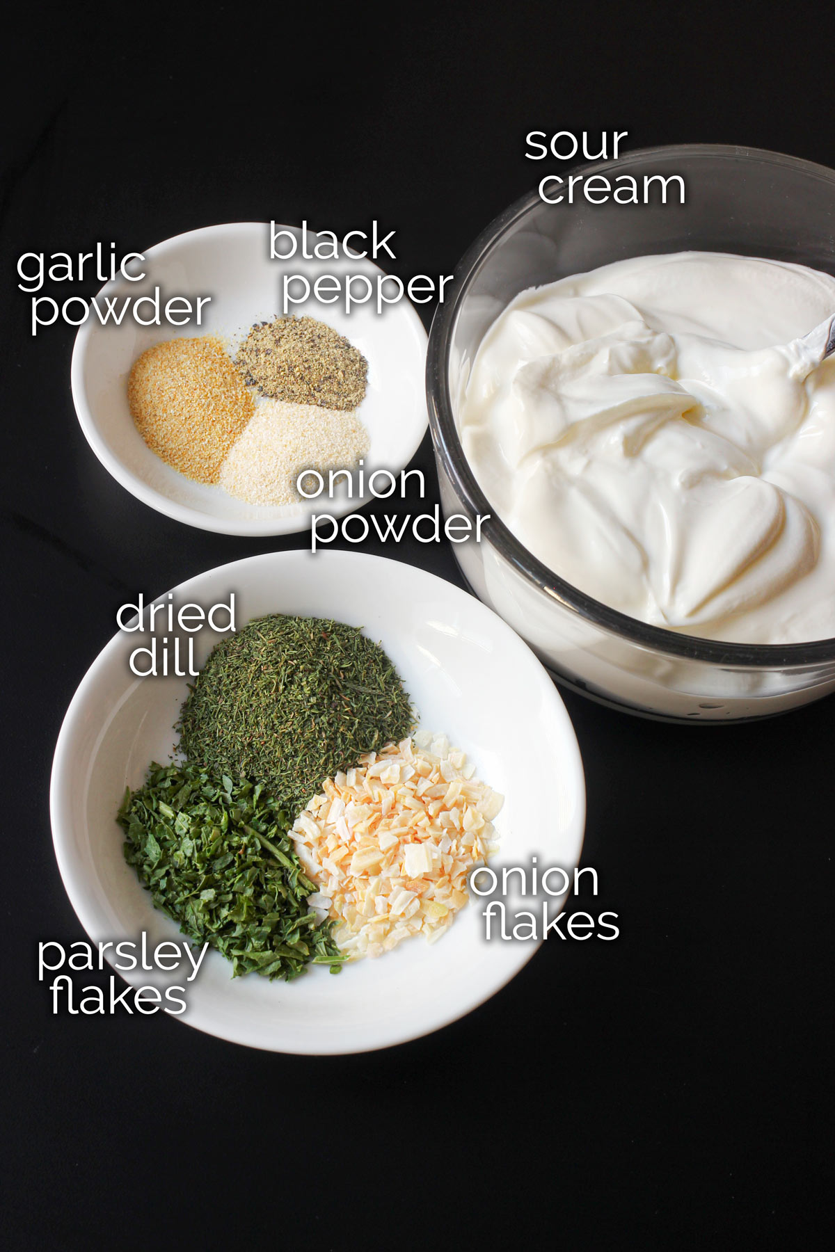 ingredients for dill dip measured and laid out on a black table top.