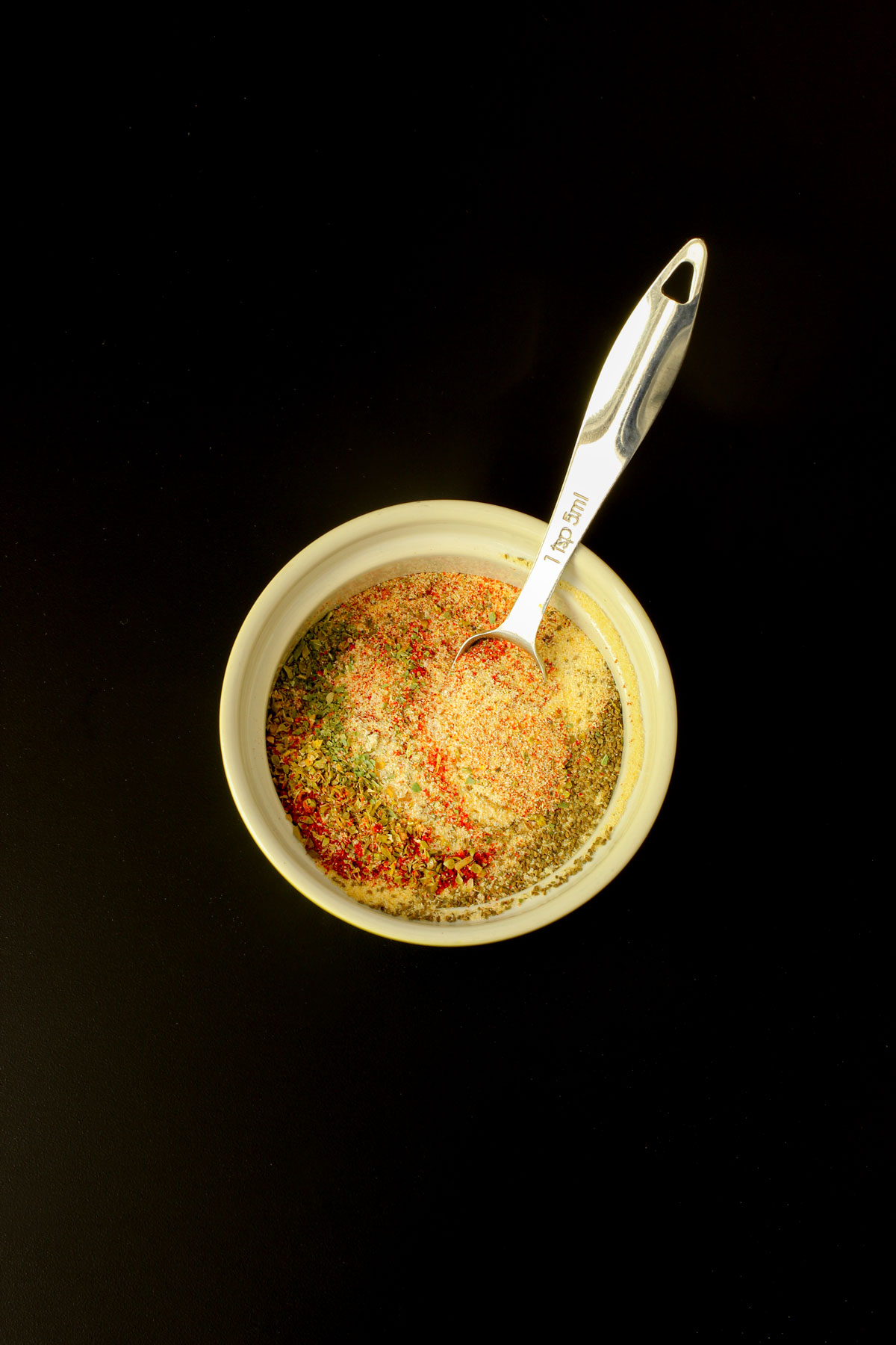 spices measured into small green bowl with measuring spoon.