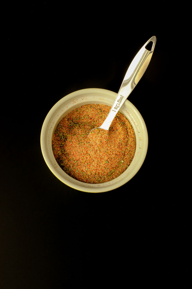 spice mix stirred completely mixed in small green bowl with measuring spoon.