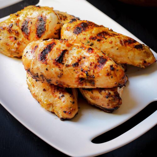 grilled spicy chicken on white platter.
