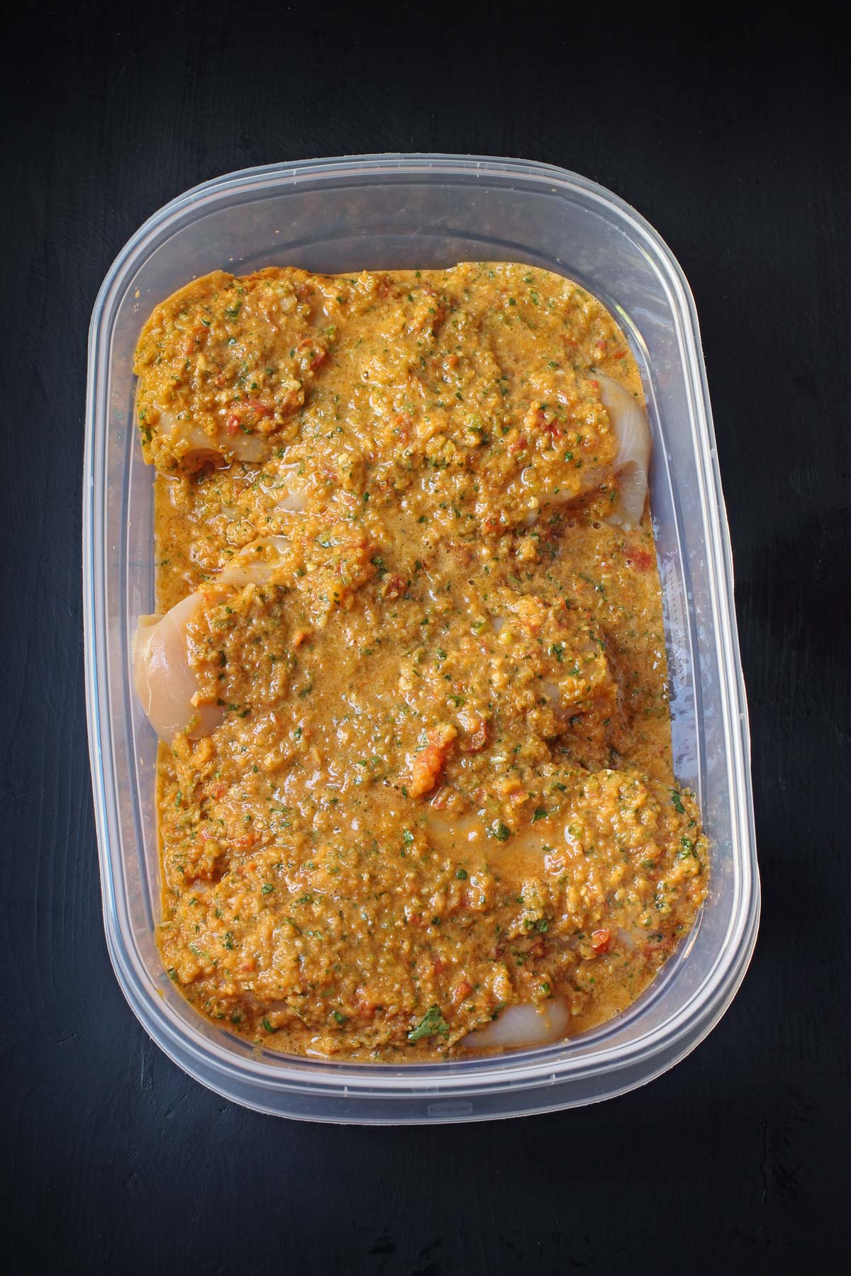 spicy chicken marinade and chicken breast in plastic container for freezing.