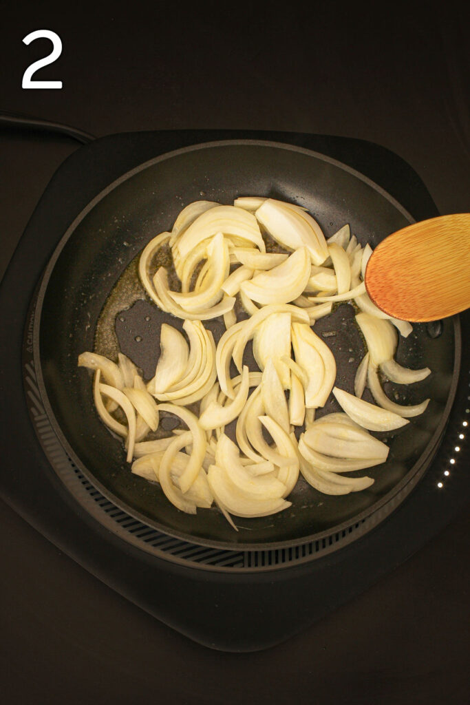 adding sliced onions to the hot oil in the skillet.