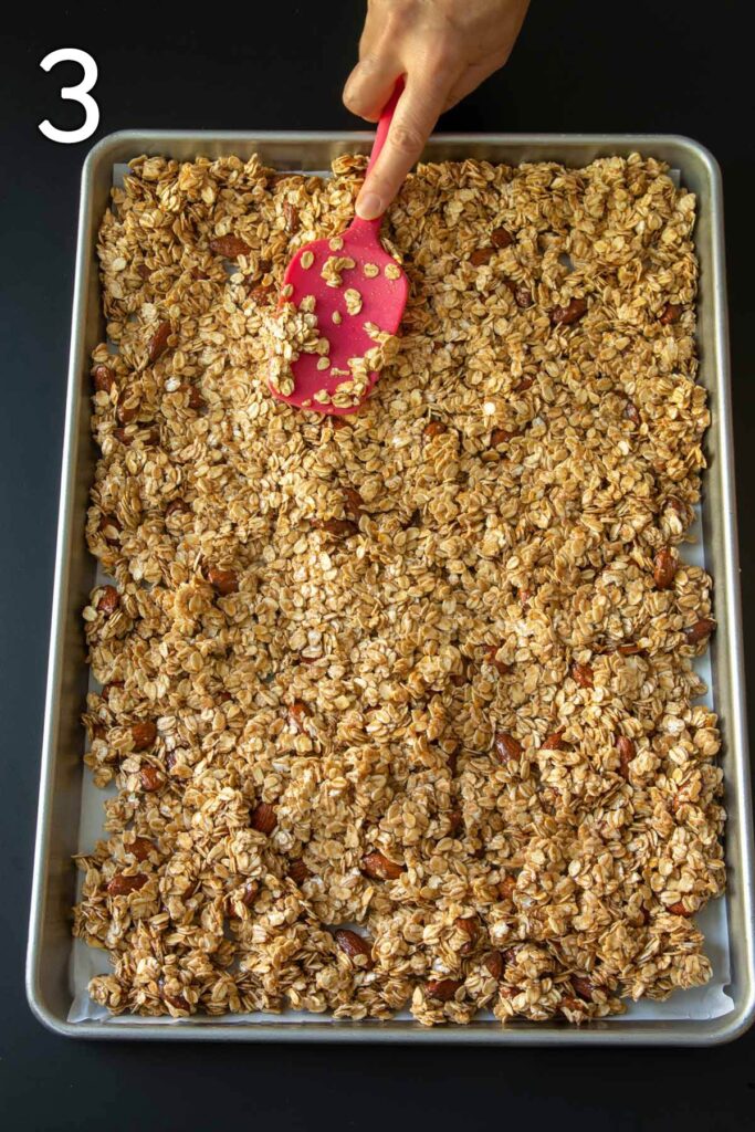 spreading granola mixture into sheet pan for baking.