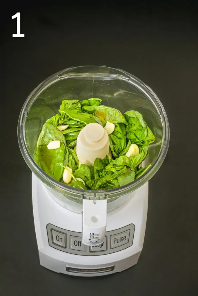 basil and garlic in food processor bowl fitted with metal blade.