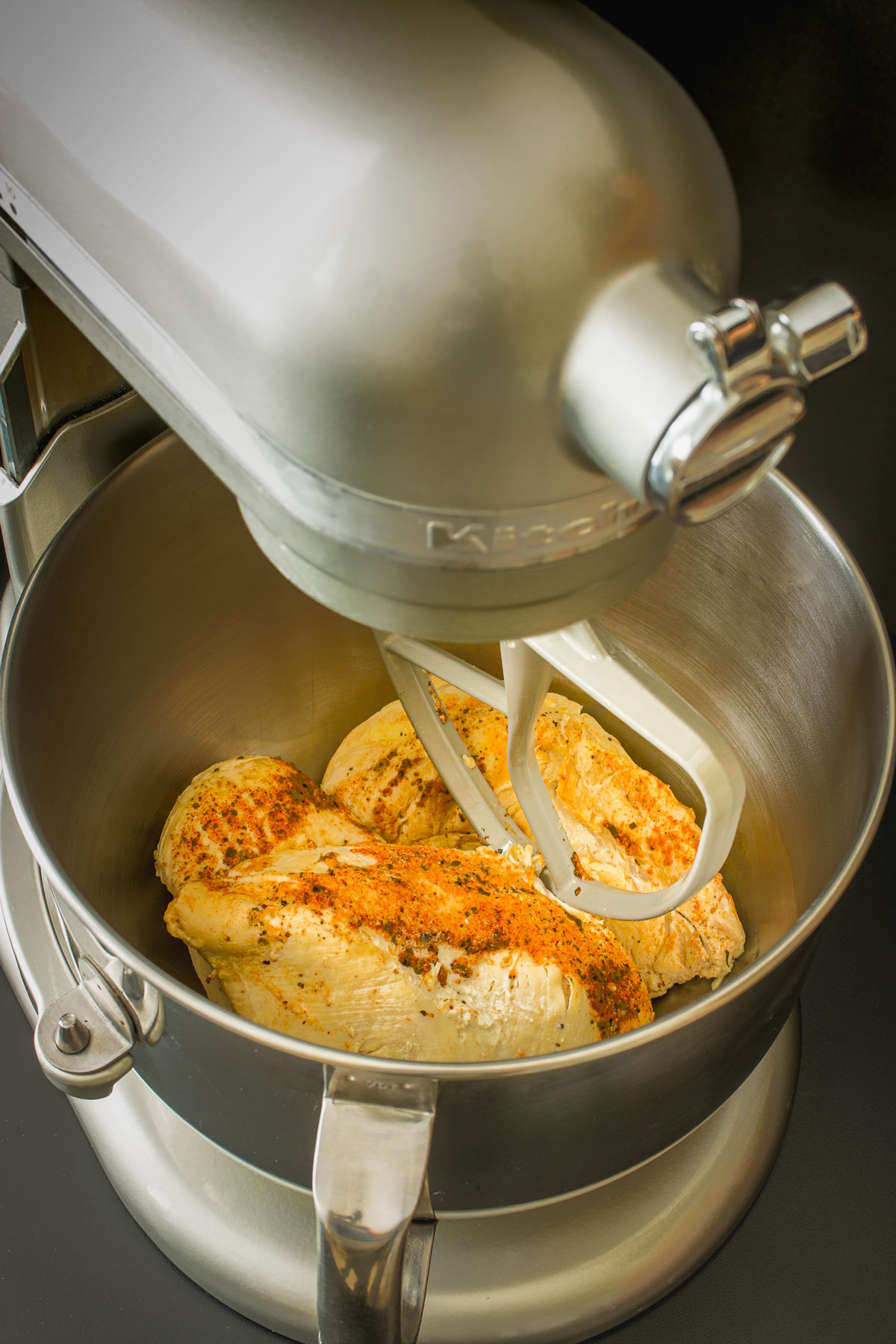 cooked chicken in stand mixer bowl fitted with paddle.