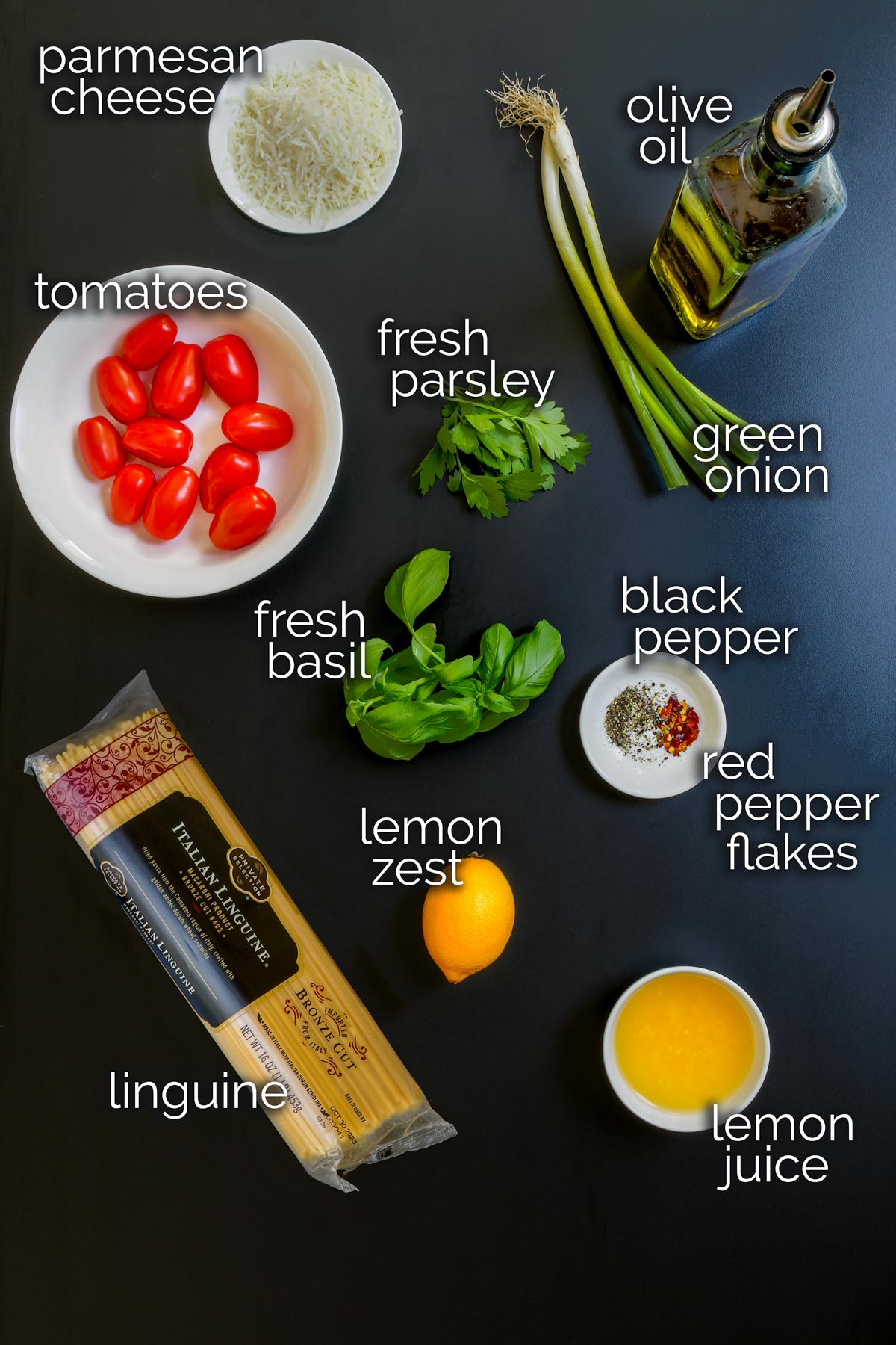 ingredients for pasta with lemon laid out on black table top.