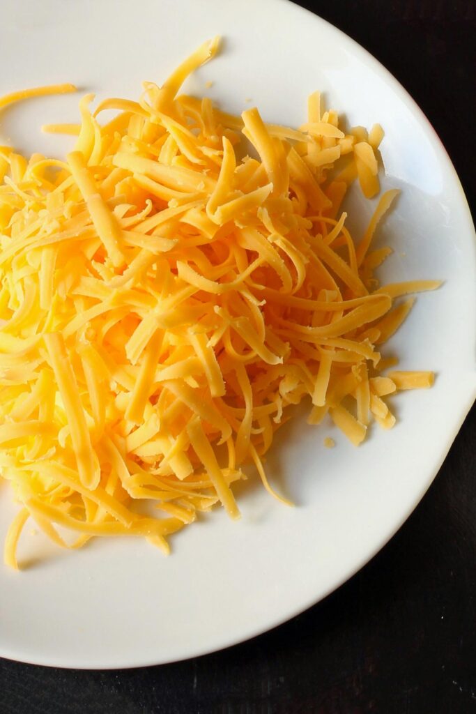 white plate with shredded cheddar cheese.