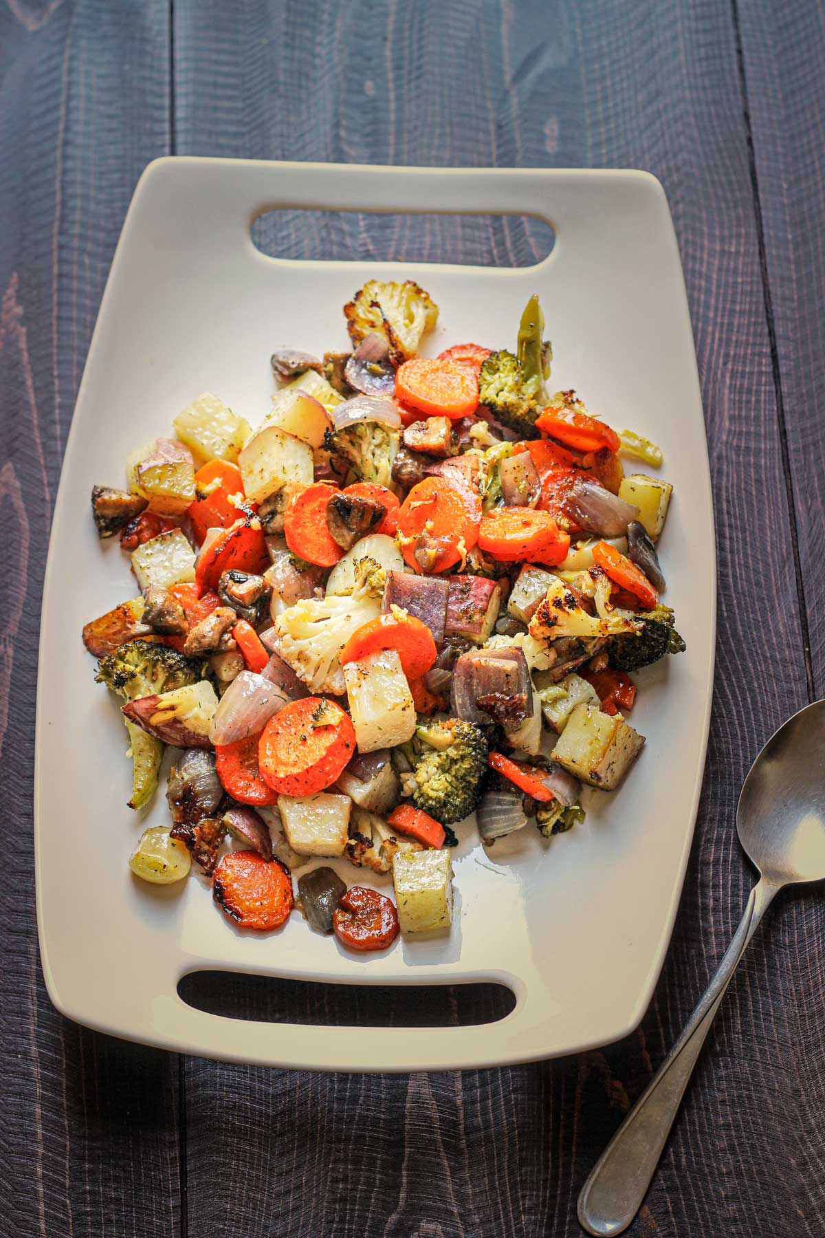 platter of roasted vegetables on table top with serving spoon.