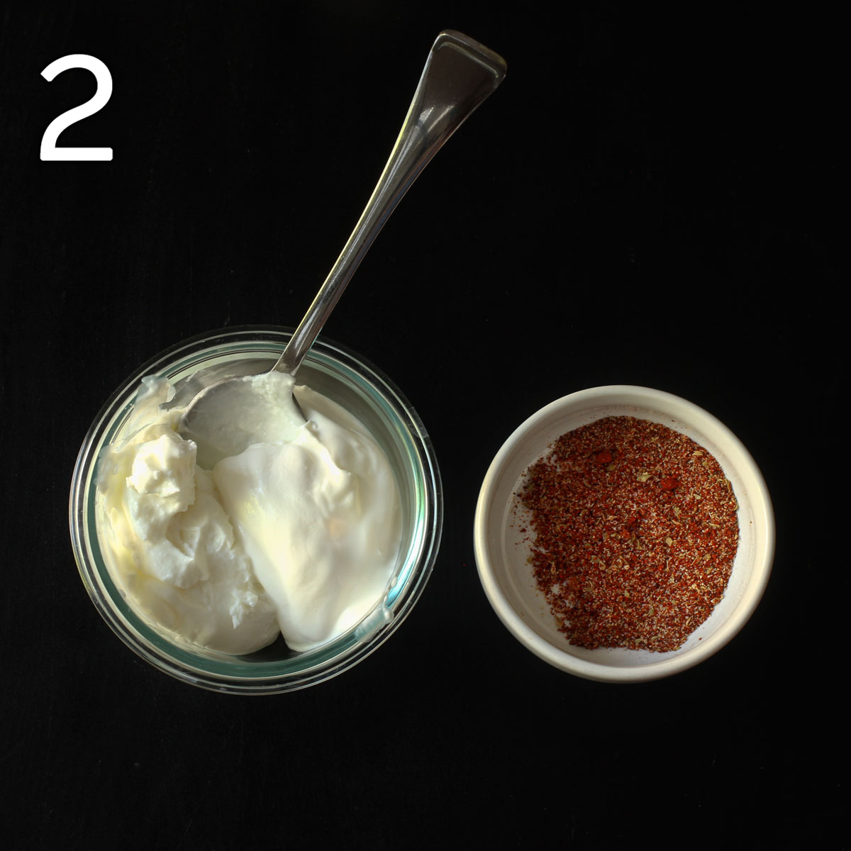 dish of sour cream with a spoon next to dish of taco seasoning.