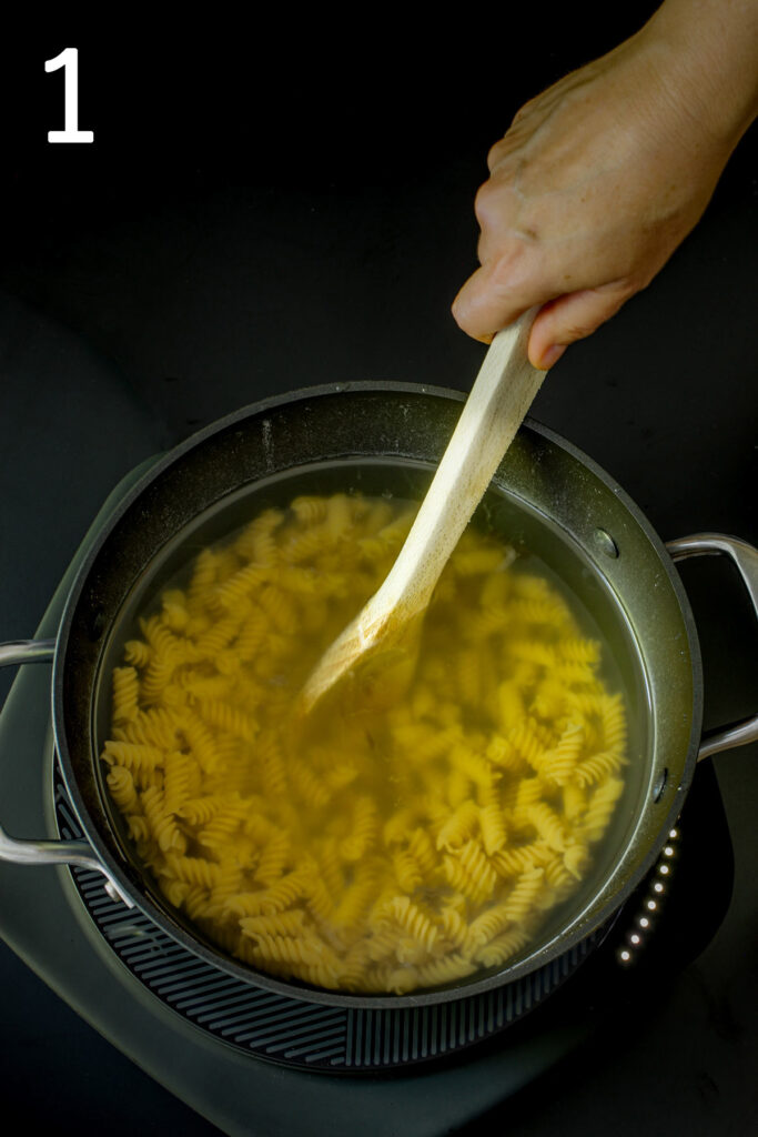 stirring noodles in a pot of hot water.