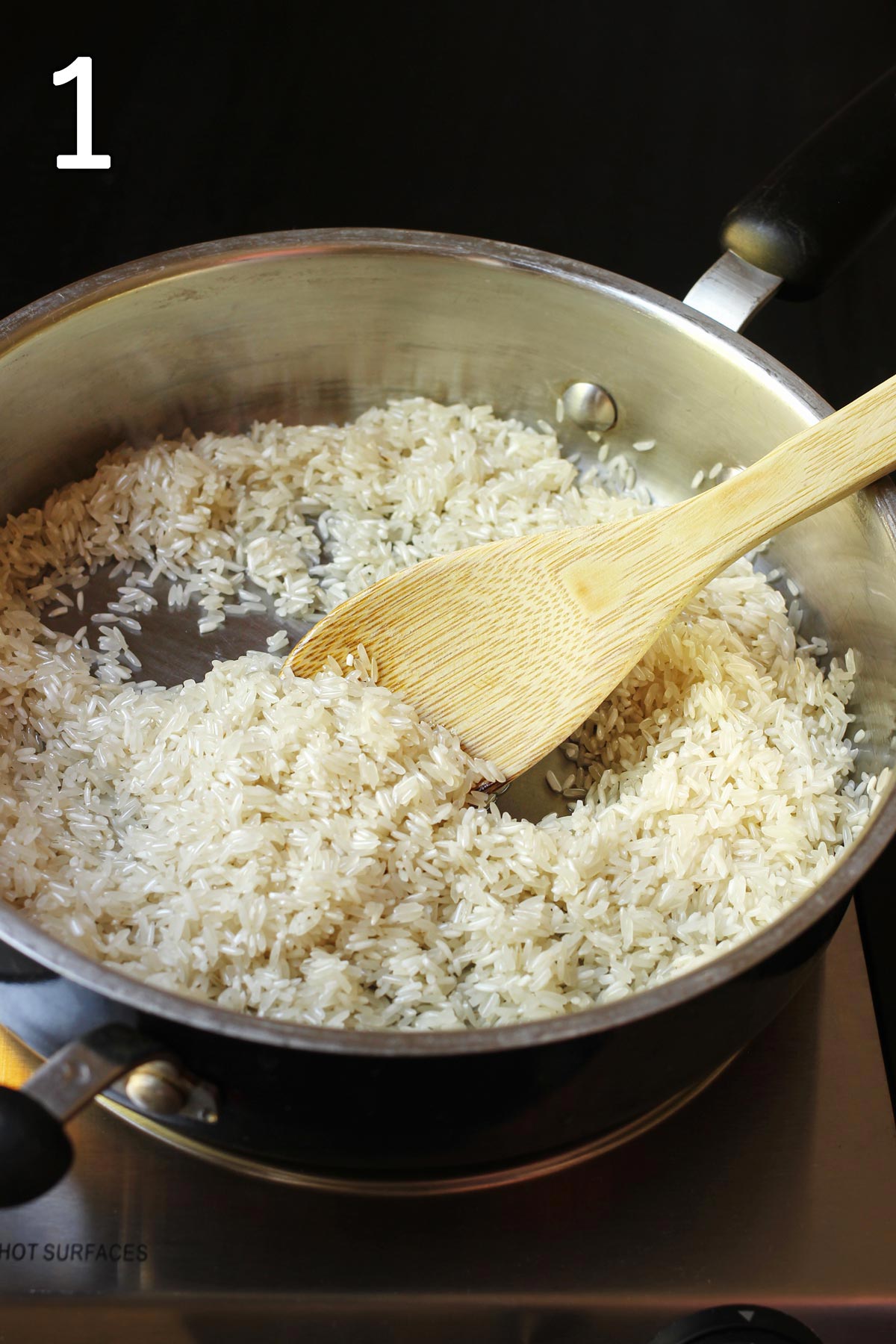 adding rice to oil in skillet and stirring with wooden spoon.