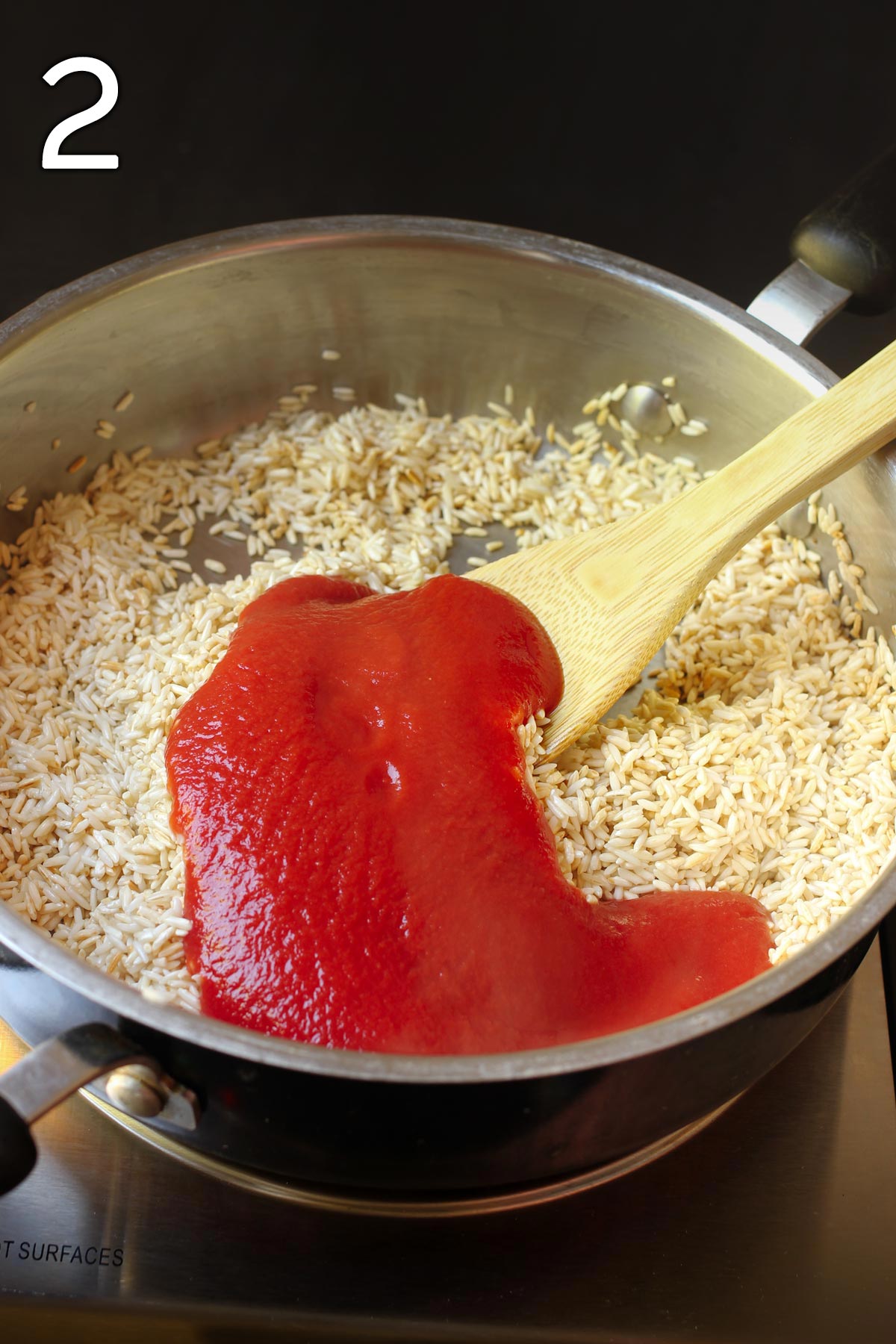 adding the tomato sauce to the rice in the skillet.