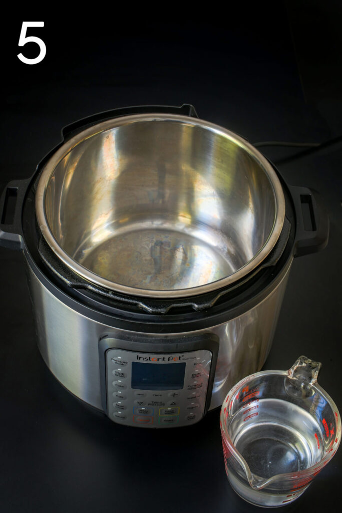 open instant pot with measuring cup of water.