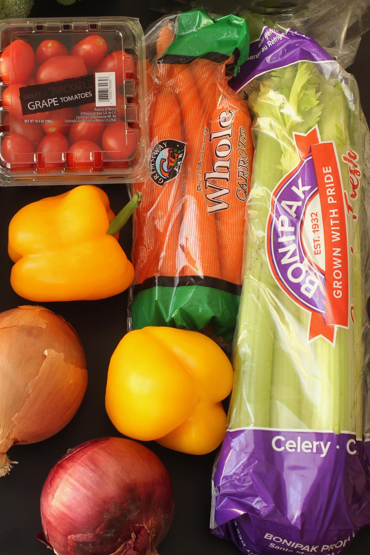 vegetables in packaging laid out on black table top in their packaging.