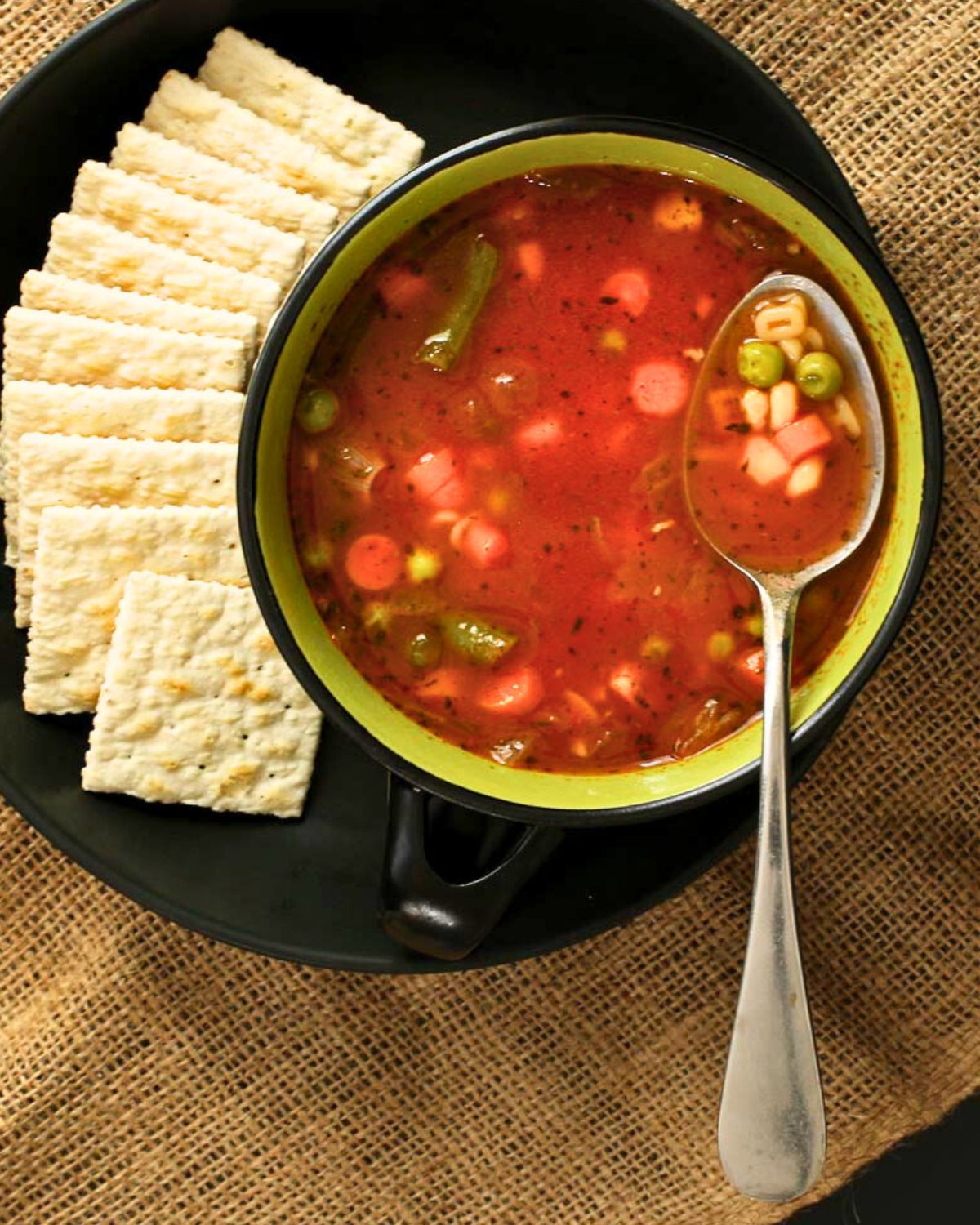 bowl of alphabet soup on plate plate with fan of saltine crackers. 