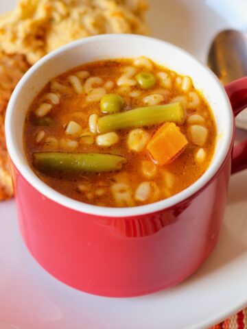 overhead shot of alphabet soup with biscuits on plate.