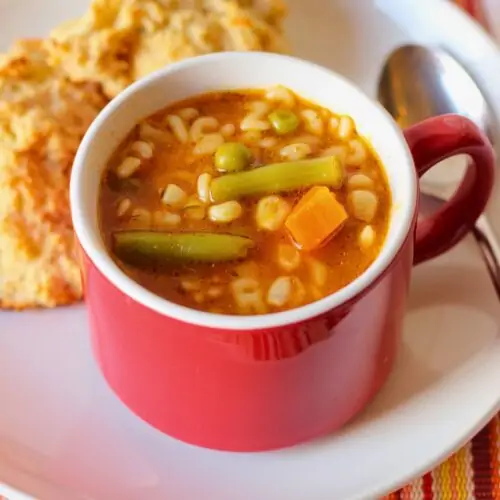 overhead shot of alphabet soup with biscuits on plate.