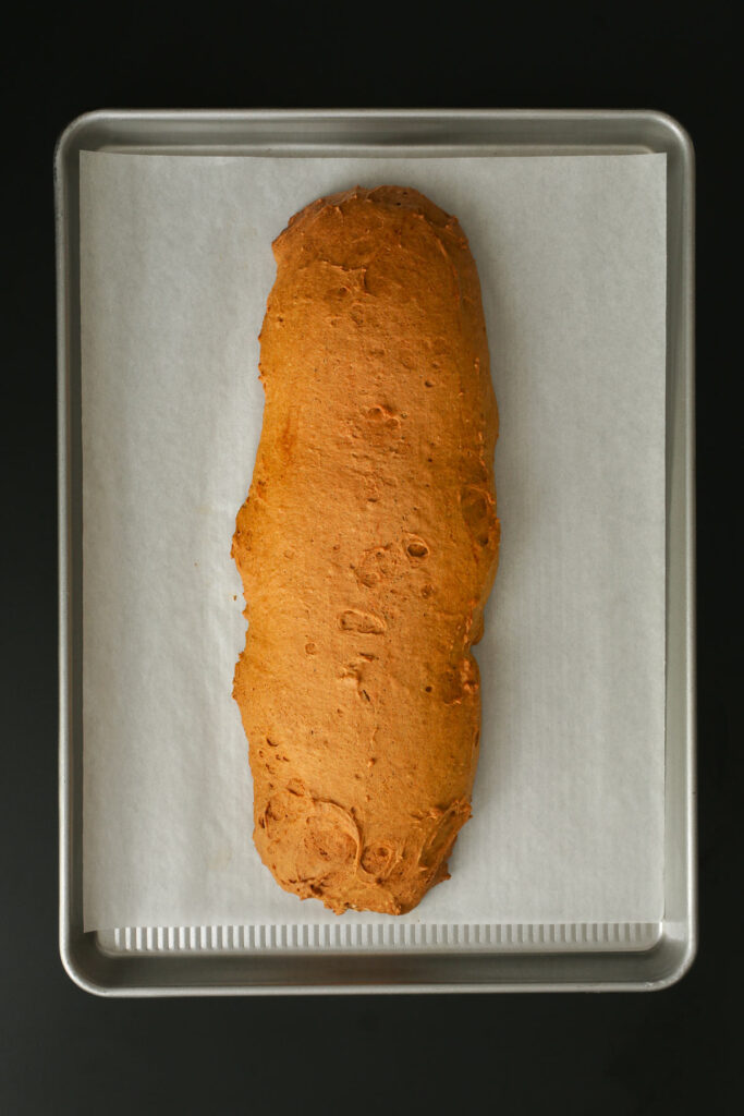 the baked biscotti log on the parchment-lined tray.