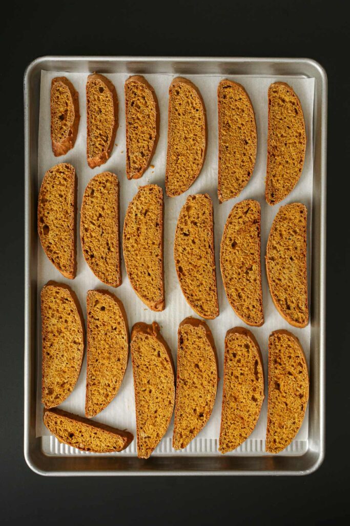 slices of biscotti laid out on parchment-lined baking sheet.