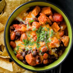 pork chili in a bowl marked ENJOY with a plate of tortilla chips.