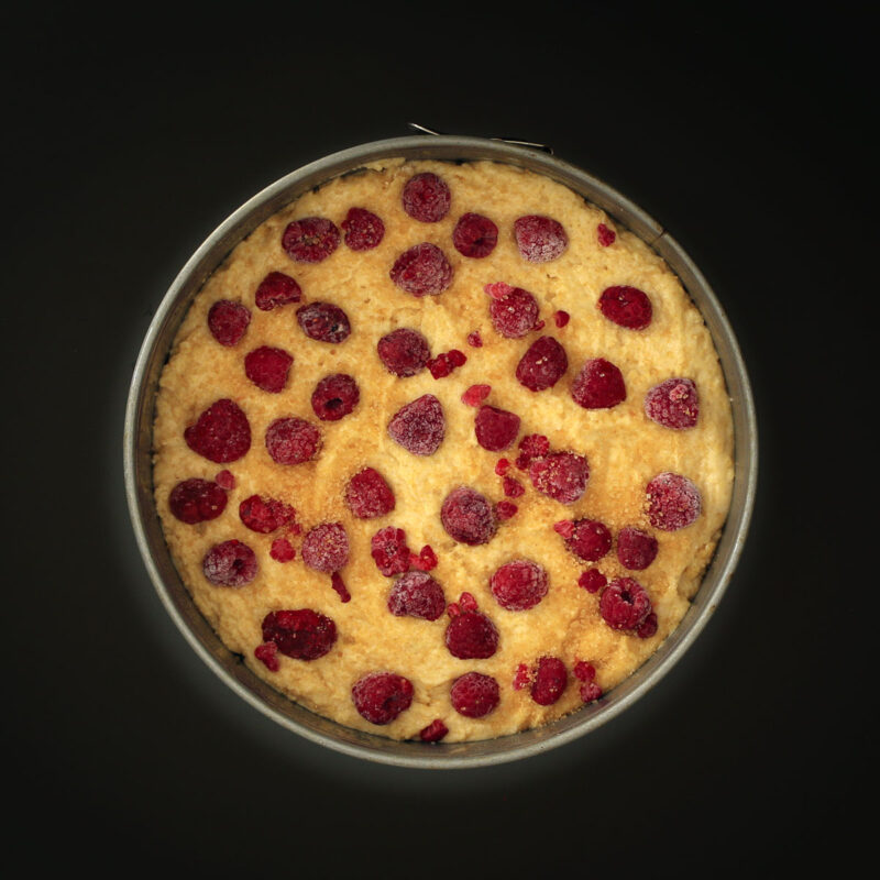 frozen raspberries and raw sugar scattered across the surface of the breakfast cake.