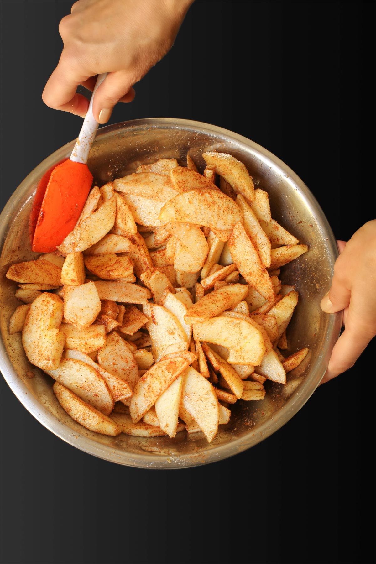 mixing apples with spices in large bowl.