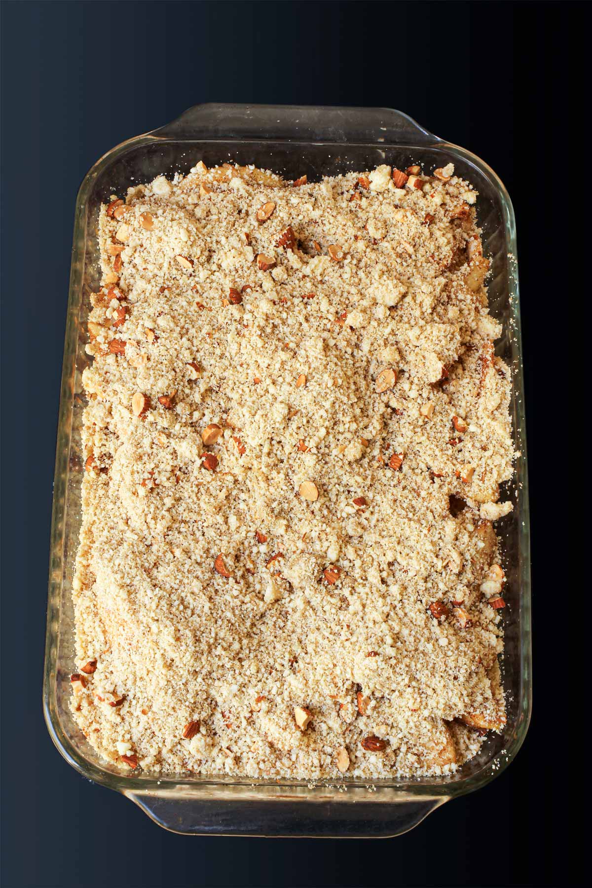 crumb topping over apples in pan ready to bake.