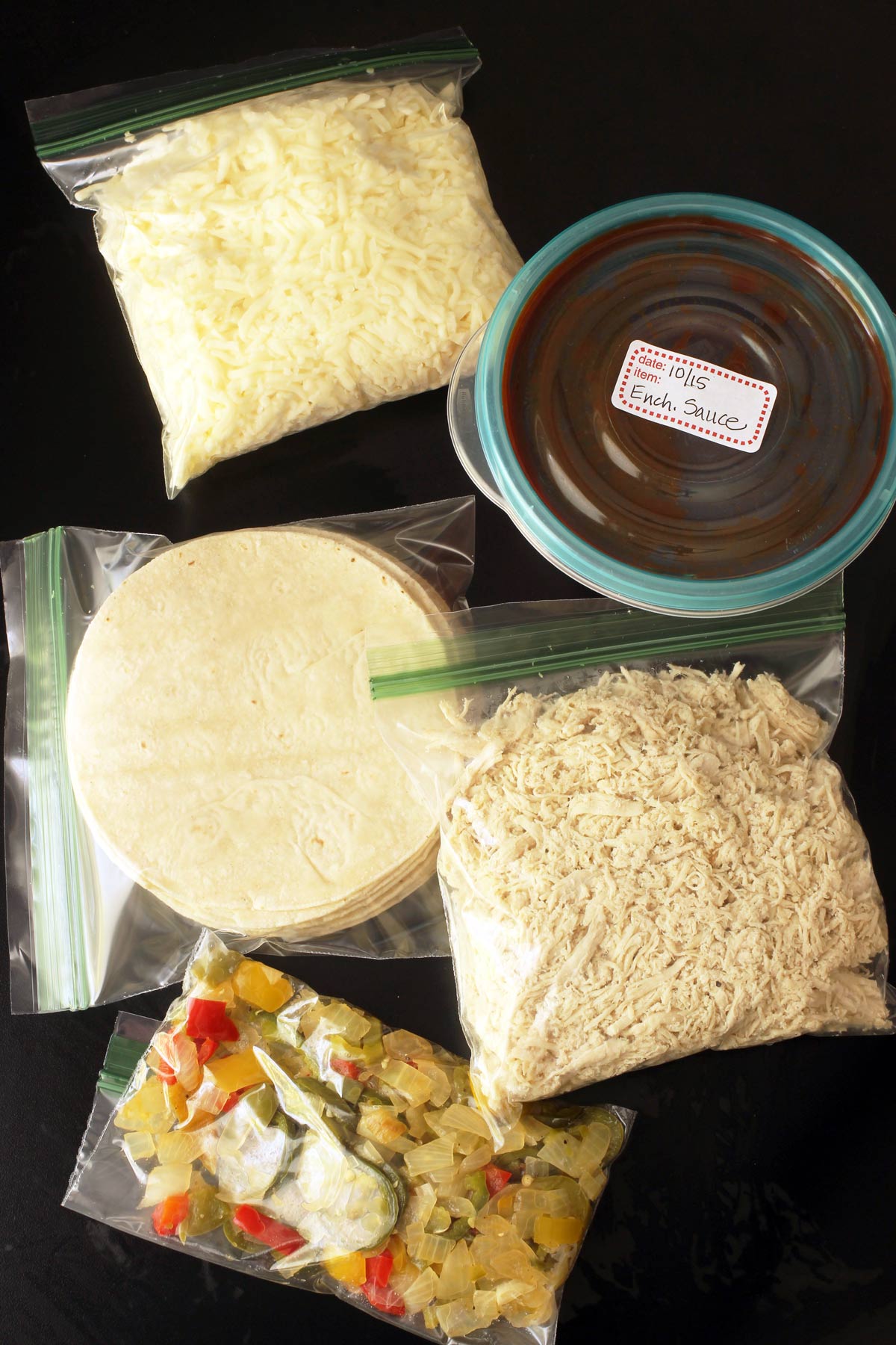 a freezer crockpot meal kit made from bags of cheese, tortillas, chicken, and sautéed veg as well as a container of sauce.