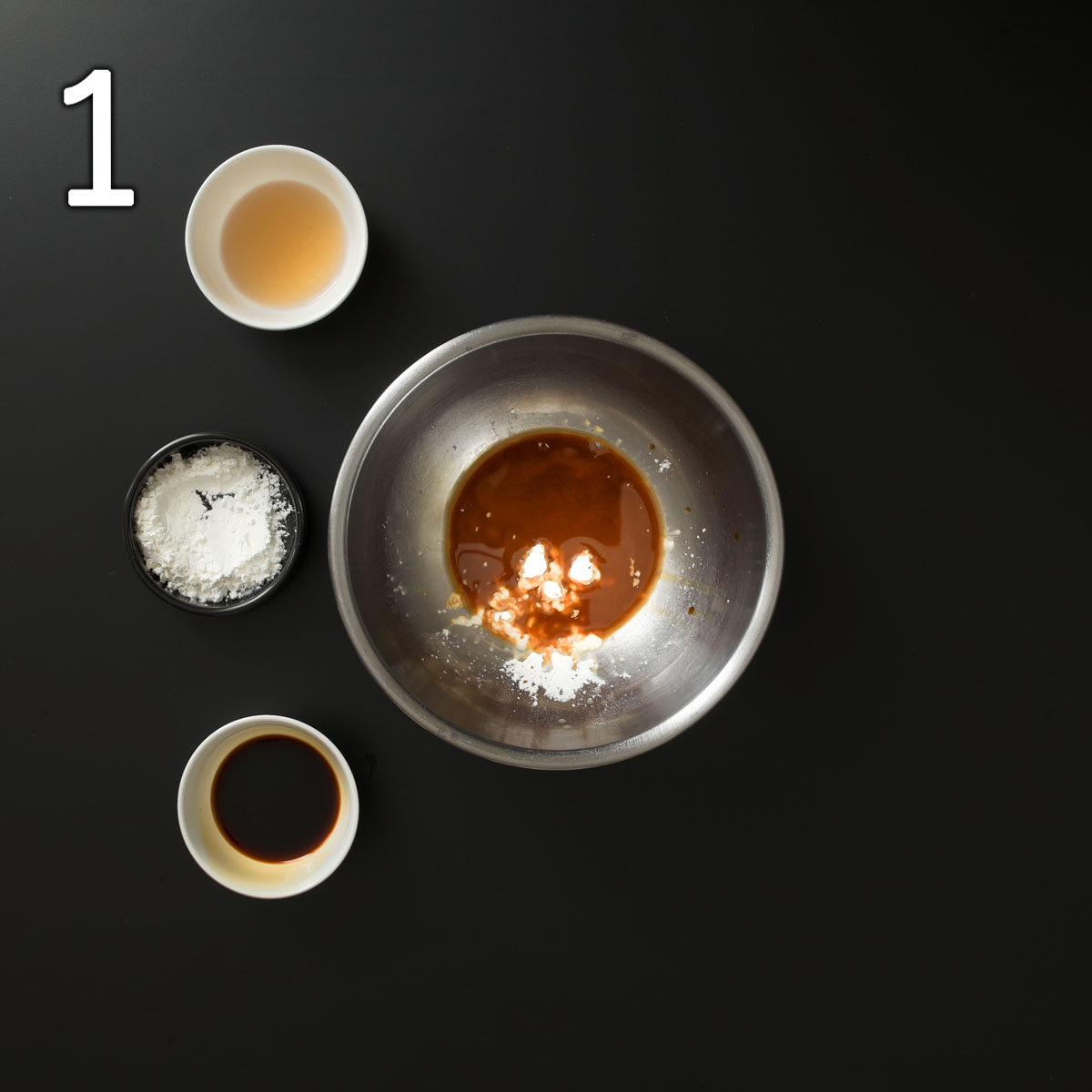bowls of sherry, soy sauce and cornstarch next to larger mixing bowl with small amounts of each of those ingredients.
