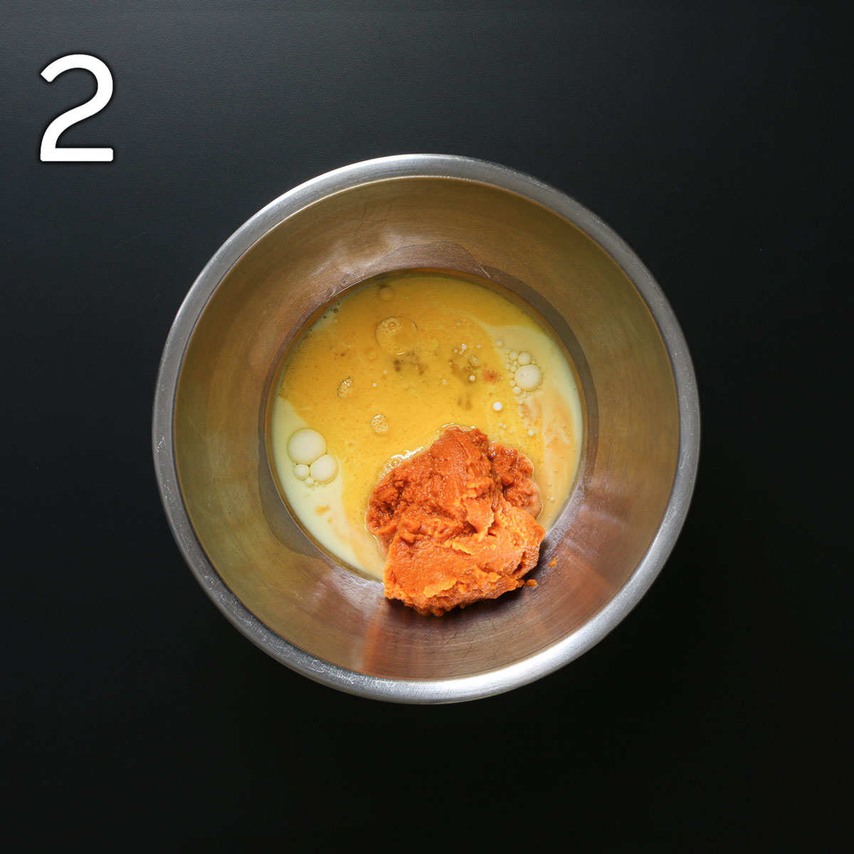 pumpkin, oil, milk, and egg in a metal mixing bowl.