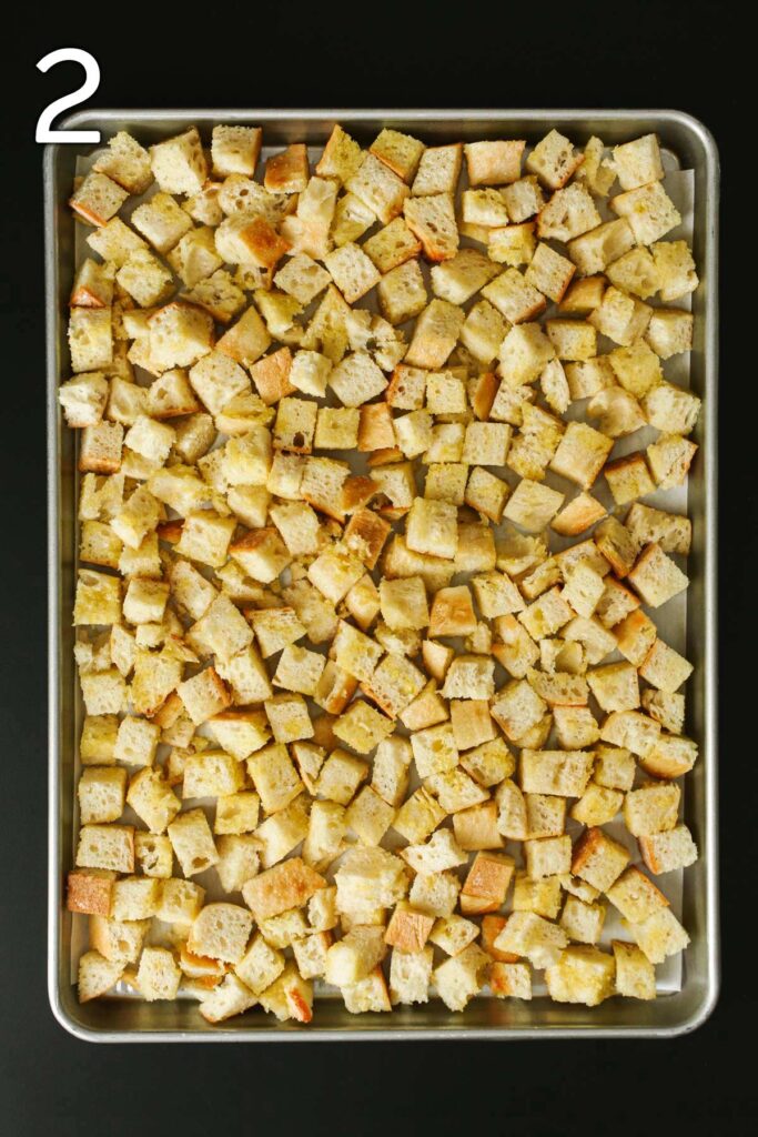 bread cubes laid out on a lined sheet pan.