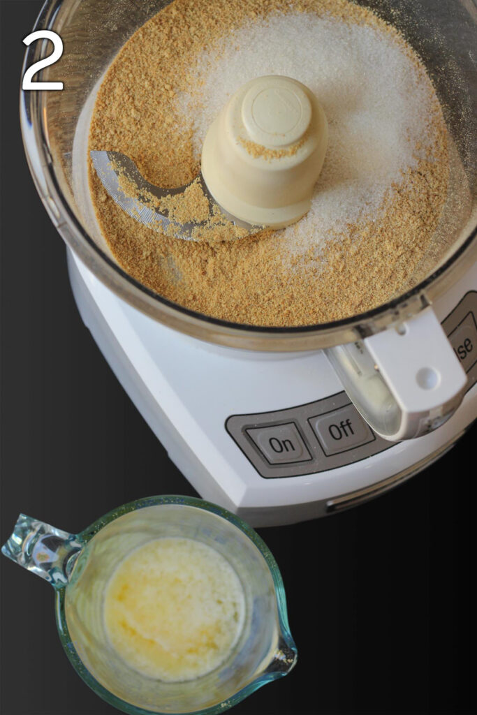 sugar added to the crumbs in the food processor with a glass measure of melted butter nearby ready to be added to the bowl.