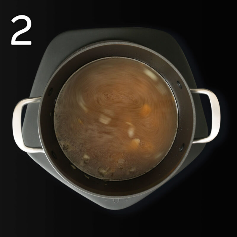 adding vegetable broth to the soup pot.