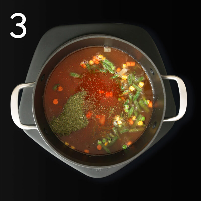 adding vegetables and spices to vegan soup.