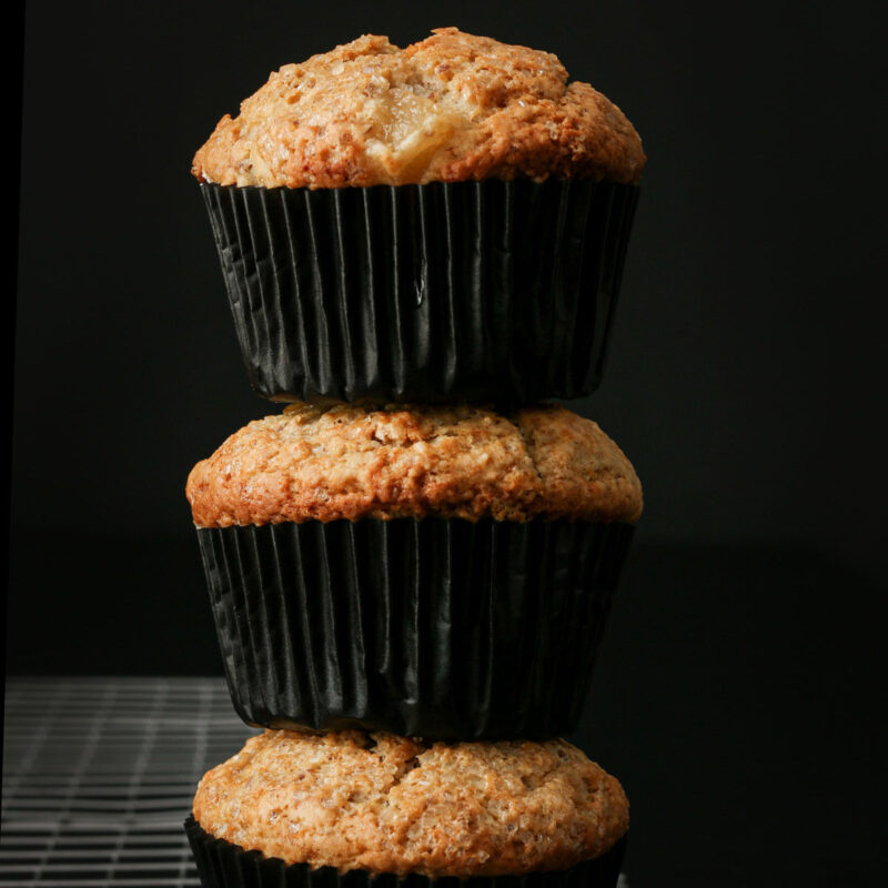 vegan muffins in black muffin papers stacked on top in a single stack.