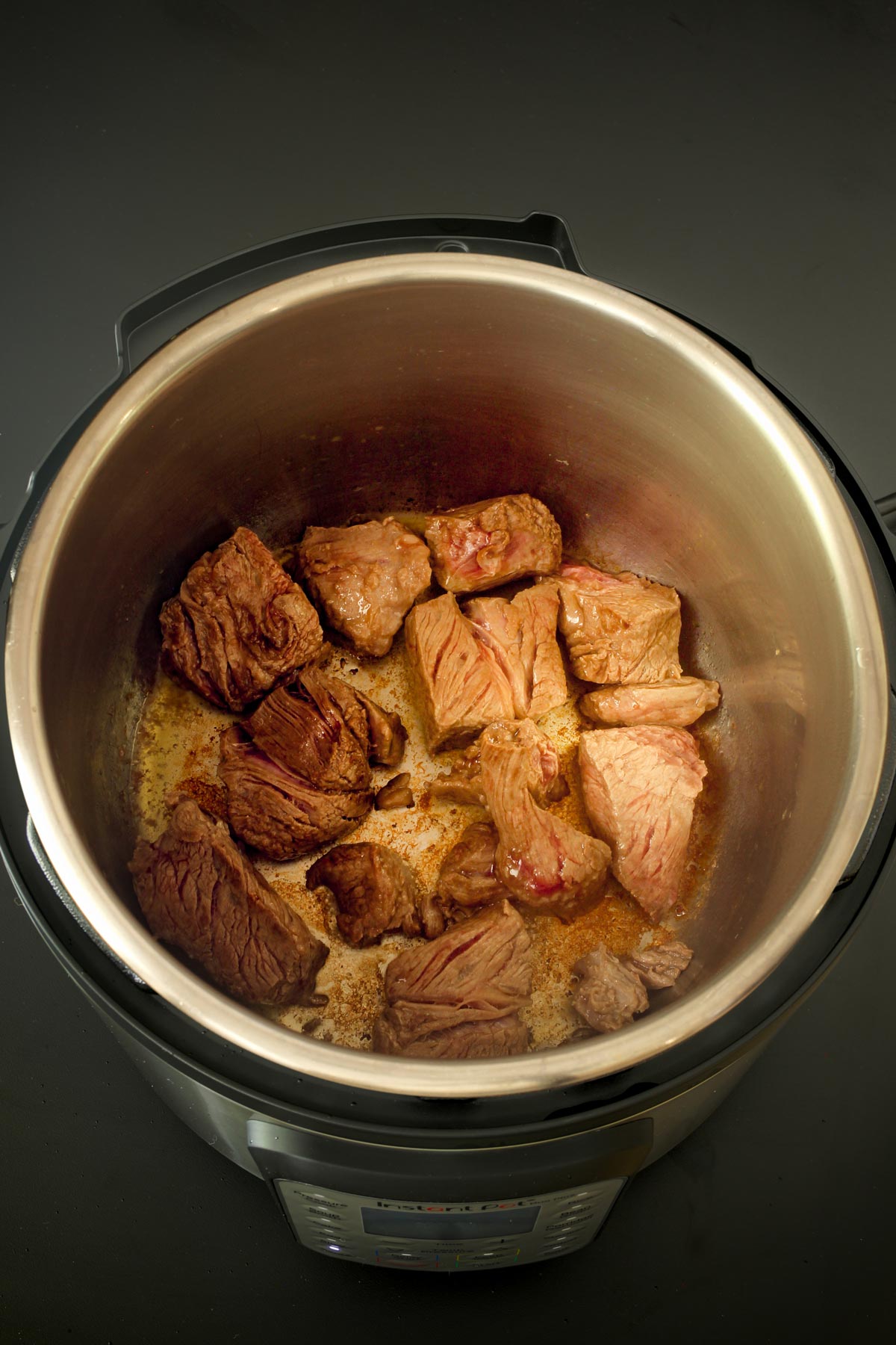 browned cubes sitting on the brown fond in the instant pot.