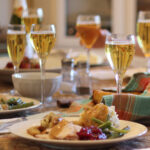 thanksgiving table set with plates of food and full wine glasses.