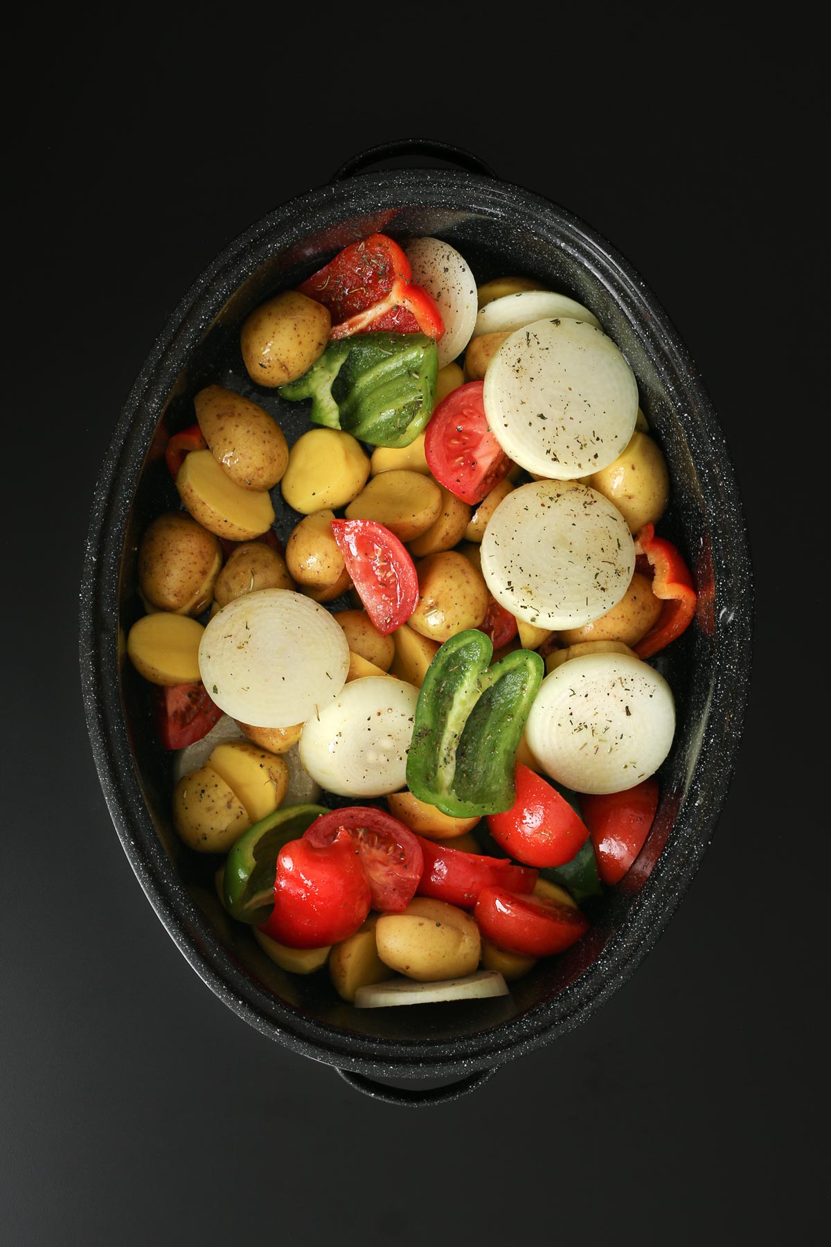 mixed vegetables in roasting pan on black work surface.