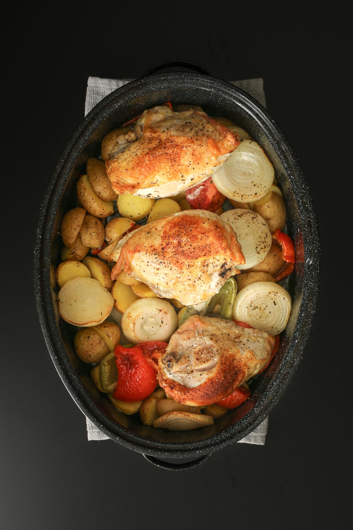 baked chicken breast atop the roasted vegetables in the roasting pan.