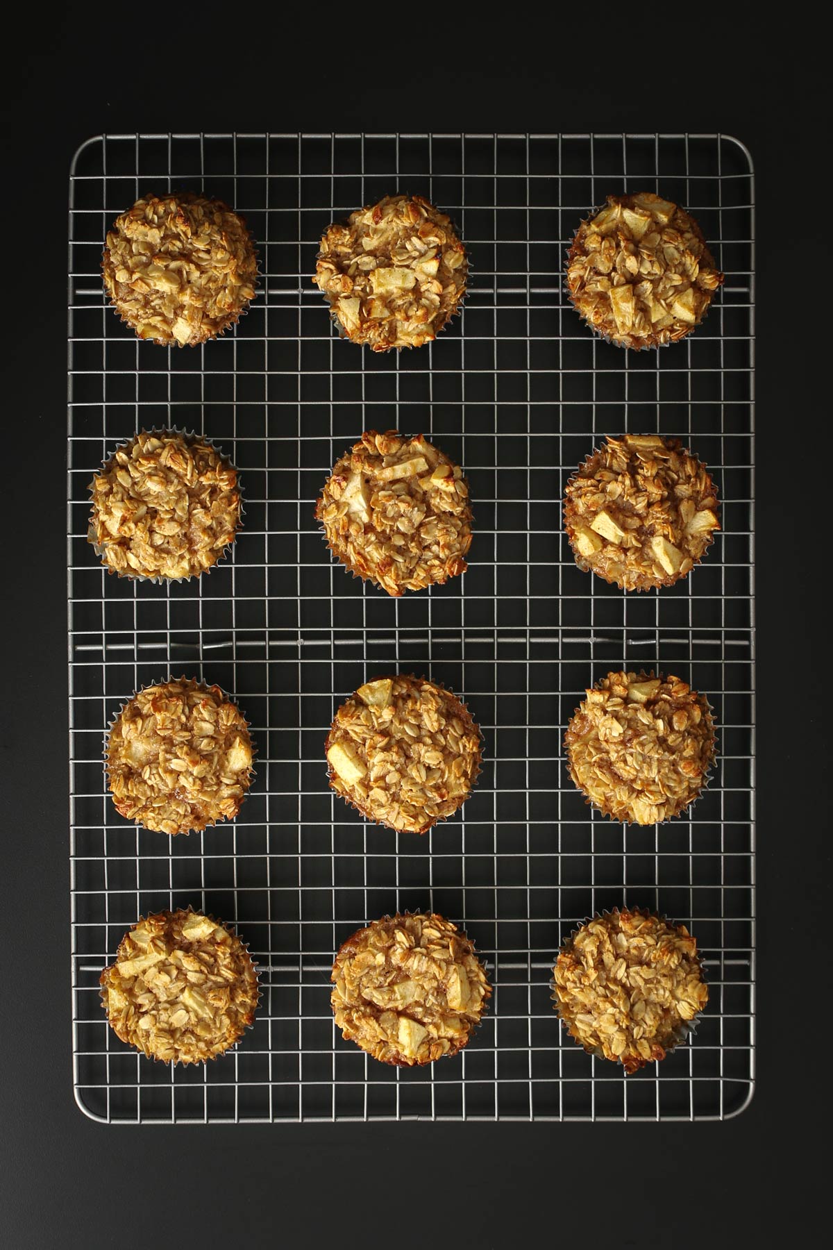 baked oatmeal cups in an array on silver wire rack on black table.