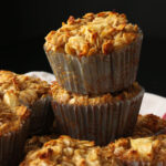 baked oatmeal cups with apple stacked on each other in a basket in front of a black backdrop.
