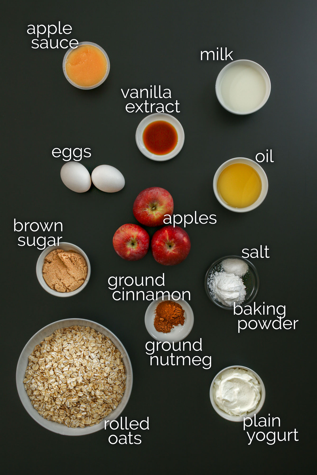 ingredients for baked oatmeal cups laid out in dishes on a black work surface.