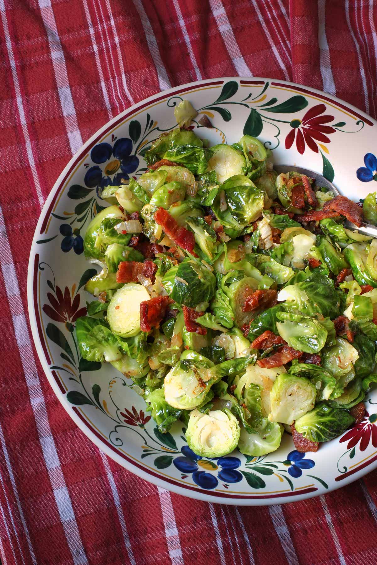 bowl of sautéed Brussels sprouts on a red cloth.