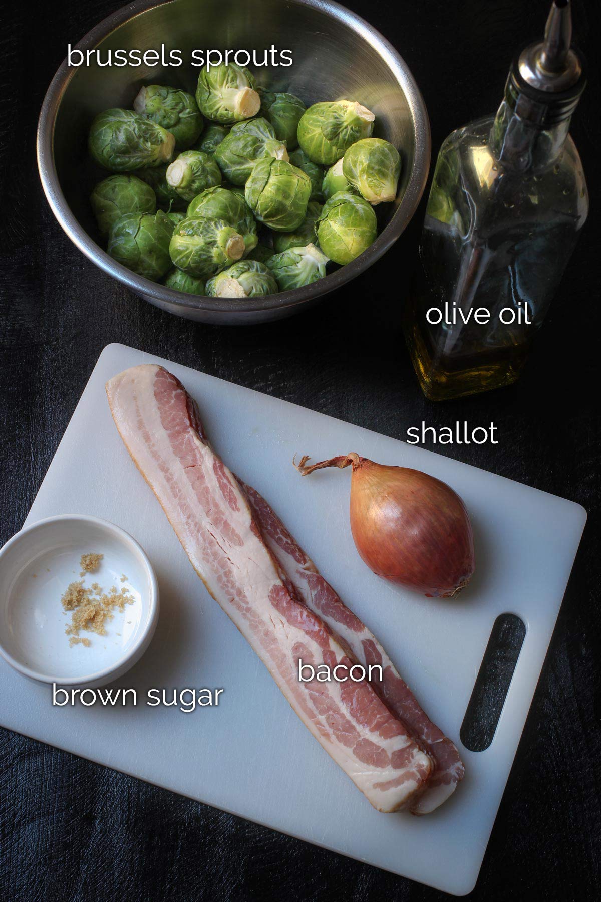 ingredients for sautéed Brussels laid out on a black table top.